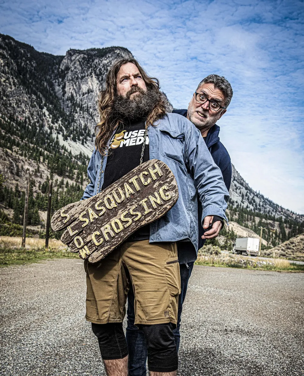 Craig Campbell holding a Sasquatch Crossing sign in the Canadian mountains